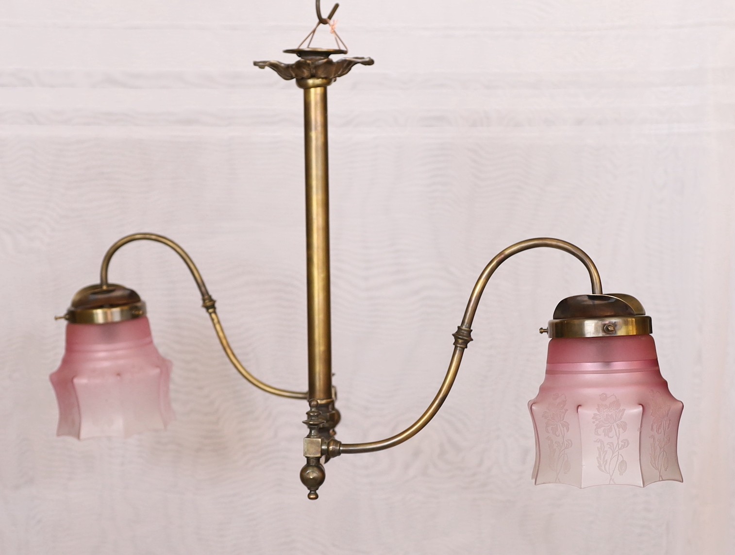 A late 19th century brass gasolier twin branch ceiling light with cranberry tinted etched glass shades, height 43cm. extends to 95cm